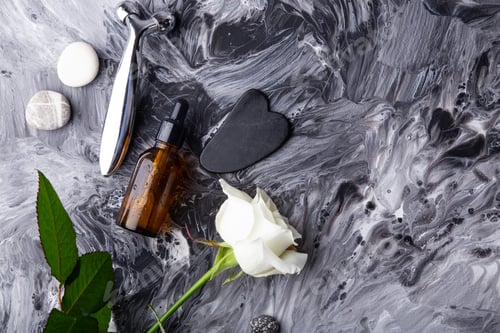 Preview: Minimalist skincare setup with massage roller, serum, gua sha on fluid art background