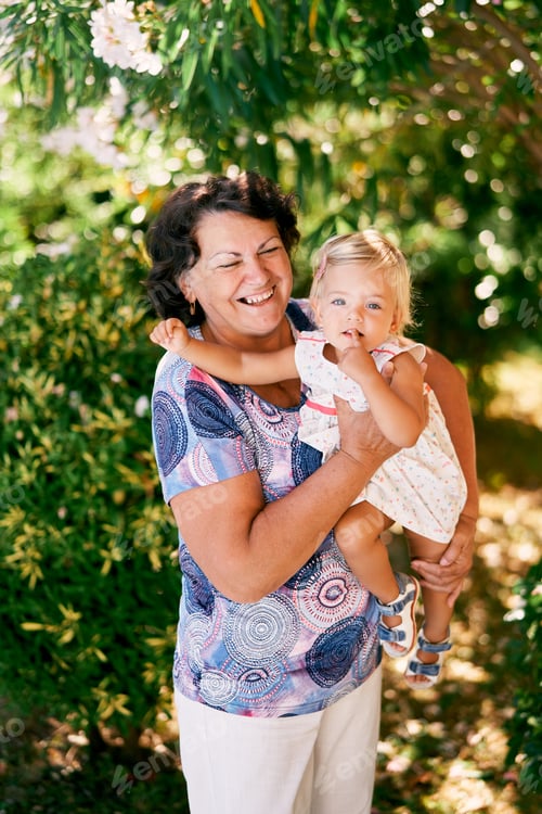 Preview: Laughing aged woman holds a little girl in her arms