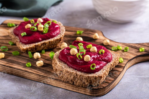 Preview: Homemade rye bread sandwiches with beetroot hummus and herbs on a cutting board