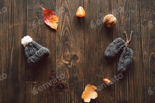 Preview: Autumn dried leaves, knitted little hat on wood background. Flat lay