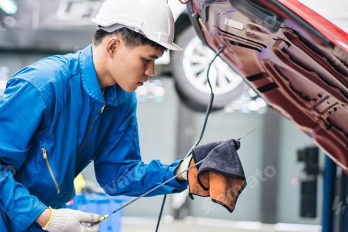 Preview: Asian male mechanic checking oil level in the car engine