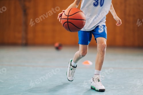 Preview: Cropped picture of junior basketball player in action dribbling a ball..