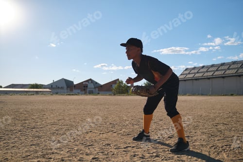 Preview: Youth baseball player concentrating on dusty sports field