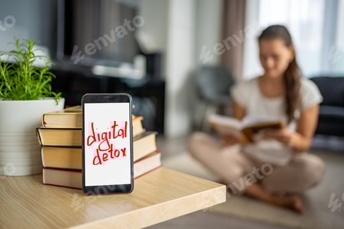 Preview: Digital detox concept photo. Smartphone with the text Digital Detox and woman reading book in the