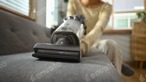 Preview: Millennial asian woman vacuuming and cleaning the dust on couch on living room.
