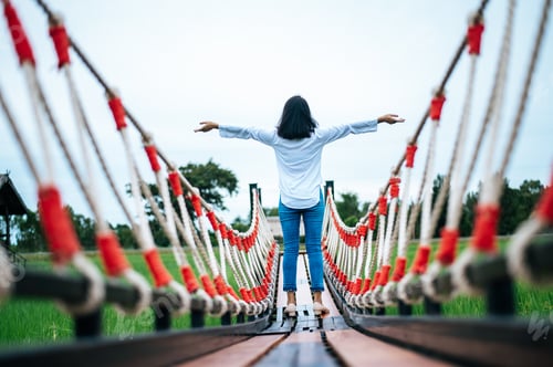 Preview: A happy woman on a wooden bridge in a green meadow on a sunny day. Happy, health, travel, lifestyle.