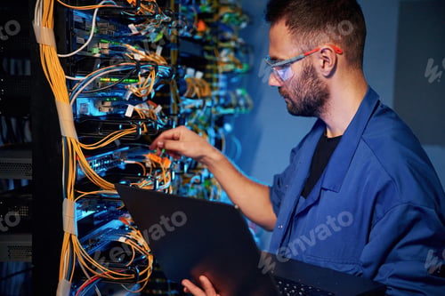 Preview: Cables management. Young man is working with internet equipment and wires in server room