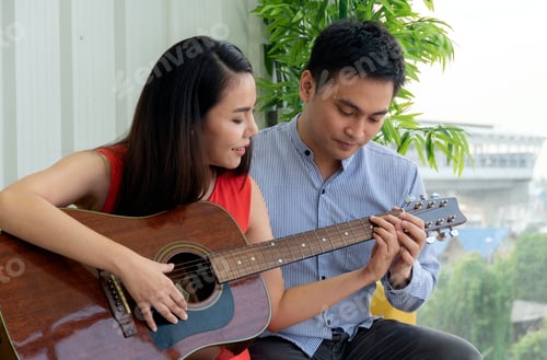 Preview: Asian man teaching woman playing guitar