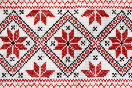 Preview: Traditional Ukrainian embroidery on white canvas as background, closeup. National handicraft