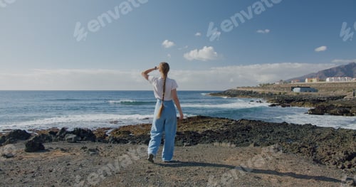Preview: Beautiful young blonde girl enjoying the view of the Atlantic Ocean. Volcanic coastline, Puerto de