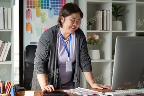 Preview: Graphic designer smiling while working at a colorful creative office desk.