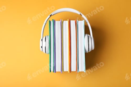 Preview: Modern headphones with hardcover books on color background, top view