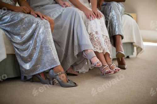 Preview: Bride and bridesmaids sitting together on sofa