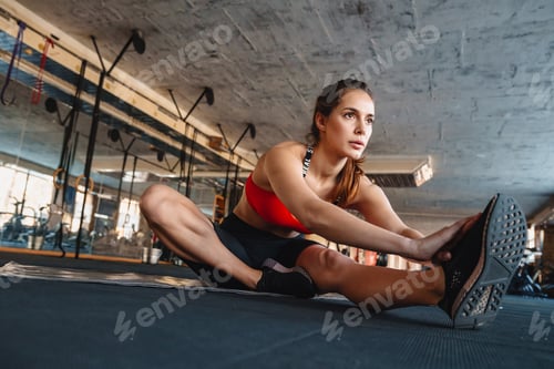 Preview: Portrait of athletic sportswoman stretching her leg while working out