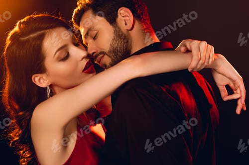 Preview: Side view of handsome man kissing elegant girlfriend with red lips on black background with lighting