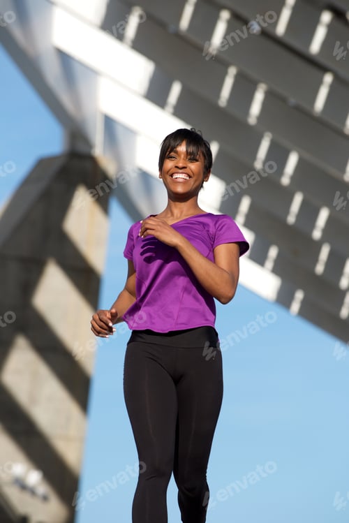 Preview: healthy black woman running outdoors and smiling