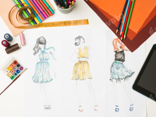 Fashion Design Sketches with Art Supplies on Desk