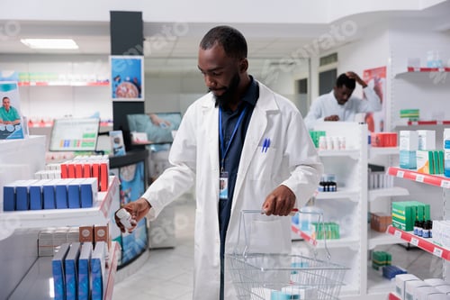 Preview: African american pharmacist putting food supplements on drugstore shelf