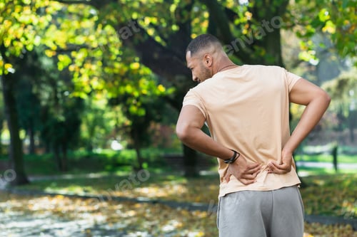Preview: Tired man after jogging in park, hispanic man has severe pain in back and muscles after fitness