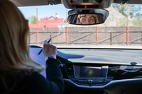 Preview: business woman working in the car and talking on the phone, face reflection in the rearview mirror