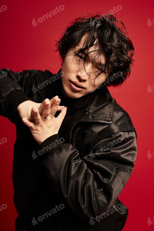Preview: Moody asian model striking a pose with intricate hand gestures in studio