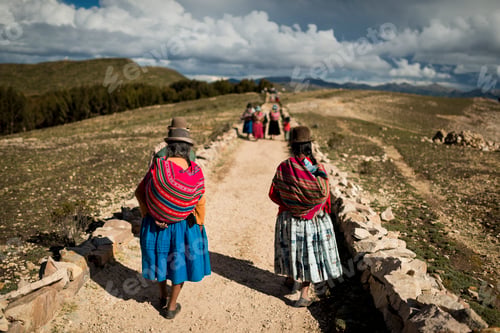 Preview: A group of traditionally dressed individuals walking on a rural road amidst a scenic landscape.