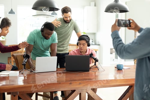 Preview: Midsection of man filming with smartphone multiracial coworkers recording podcast in office