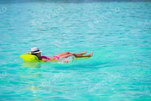 Preview: Woman relaxing on inflatable air mattress at turquoise water