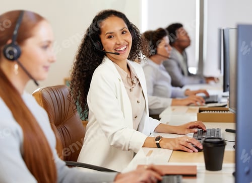 Preview: Portrait of a young call centre agent working on a computer alongside her colleagues in an office
