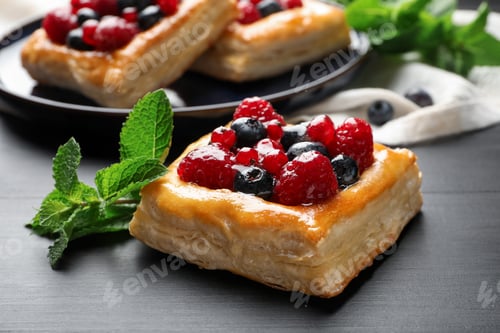 Preview: Tasty puff pastries with berries and mint on grey wooden table, closeup
