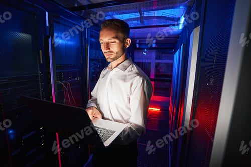 Preview: System technician running diagnostic of server racks with laptop