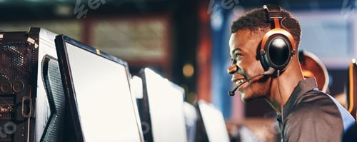 Preview: Side view of a happy excited african guy, professional gamer wearing headphones participating in