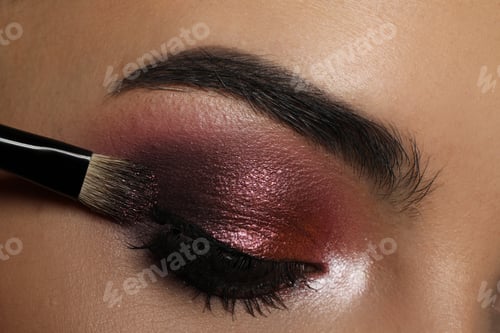 Preview: Applying dark eye shadow with brush onto woman's face, closeup. Beautiful evening makeup