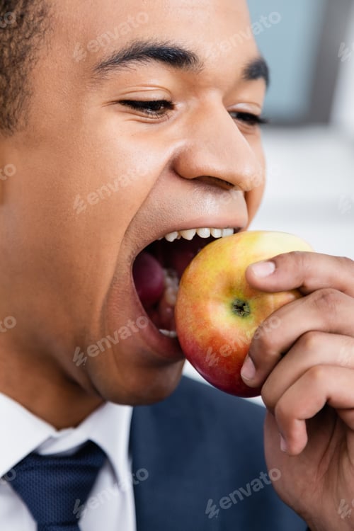 Preview: african american businessman biting apple