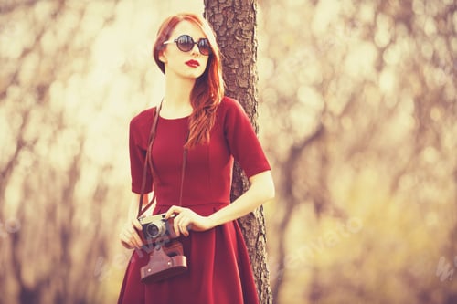 Preview: Redhead women in a park with camera