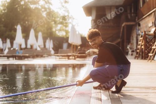 Preview: Pool cleaner cleaning swimming pool with cleaning net at luxury resort