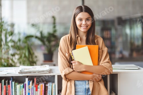 Preview: Portrait of smiling teenage girl holding book looking at camera. Back to school, education concept