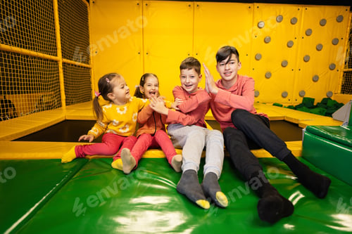 Preview: Kids together sit at playground park and give high five each other.