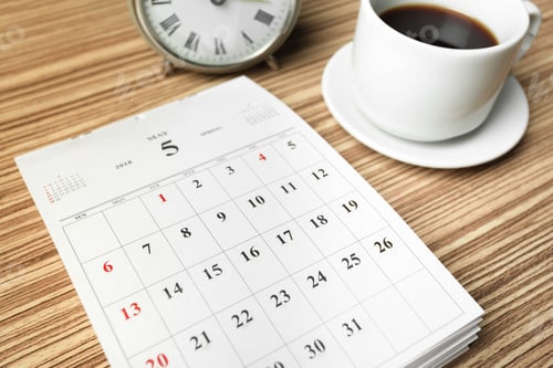 Preview: Coffee cup and clock next to a calendar on a wooden table in a morning setting
