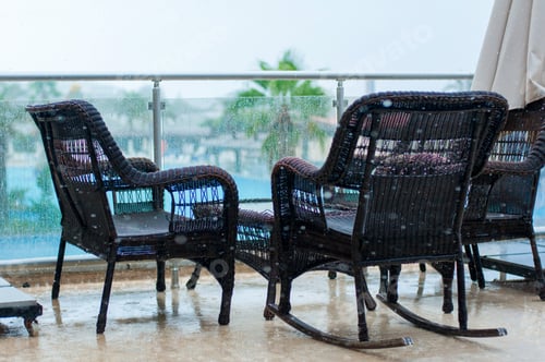 Preview: Woven chairs on the balcony near the pool on rainy day