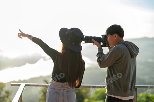 Preview: Sunrise morning traveler man hold camera zoom lens shooting beautiful girl on viewing platform