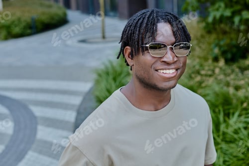 Preview: Handsome young man enjoying a sunny stroll in a modern urban park setting