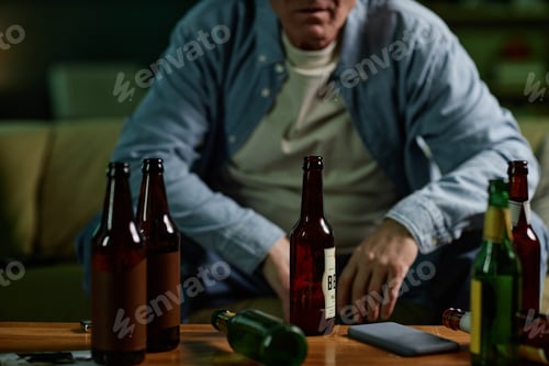 Preview: Man Sitting with Alcoholic Beverages on Table Thinking
