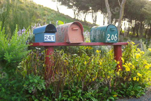 Preview: View of three old and rustic postboxes on a red bank in New Zealand