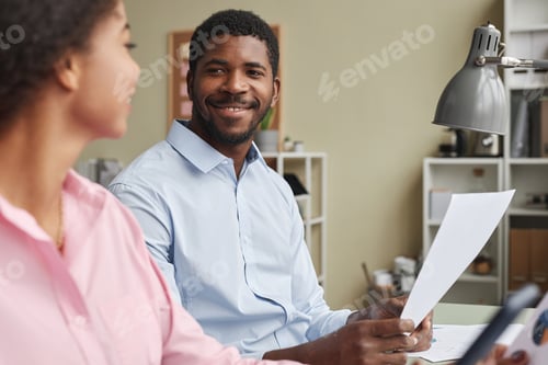 Preview: Portrait of two smiling man and woman collaborating on project together sitting at desk in office
