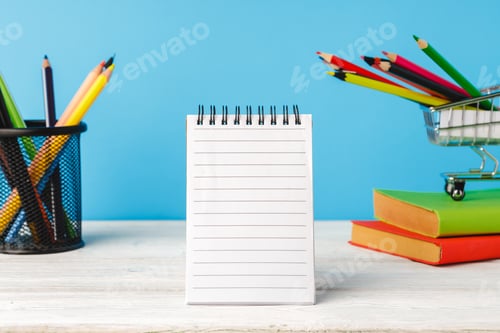 Preview: School supplies on wooden desk against blue background