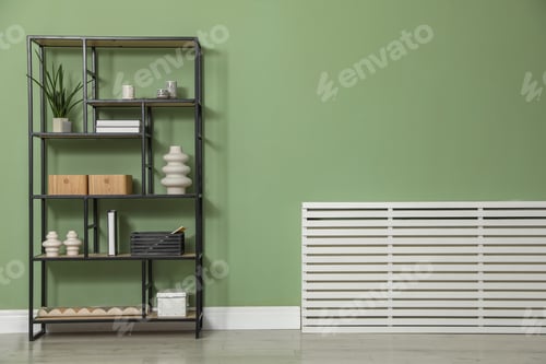 Preview: Wooden shelving unit with different home decor near olive wall indoors