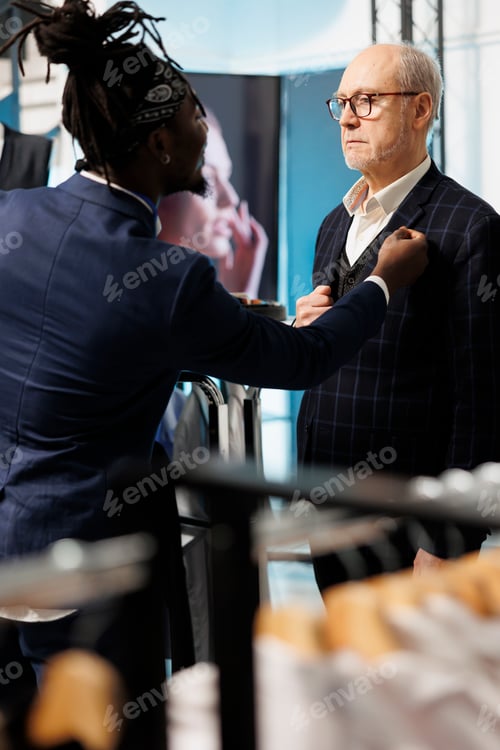 Preview: African american employee helping stylish man with suit