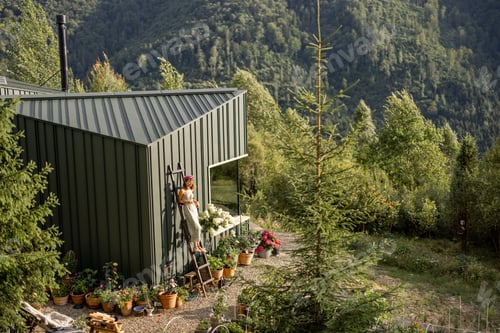 Preview: Woman on Ladder by Eco-Friendly House in Green Mountain Garden