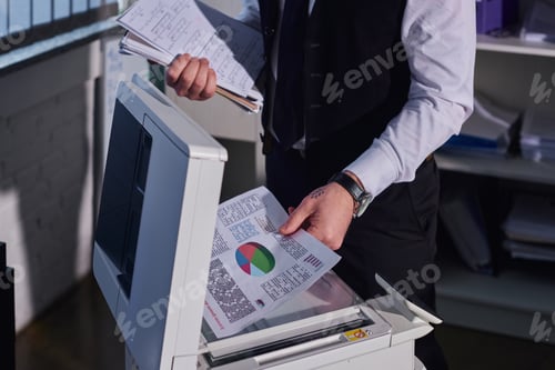 Preview: cropped view of tattooed businessman copying documents with graphs while working late in office